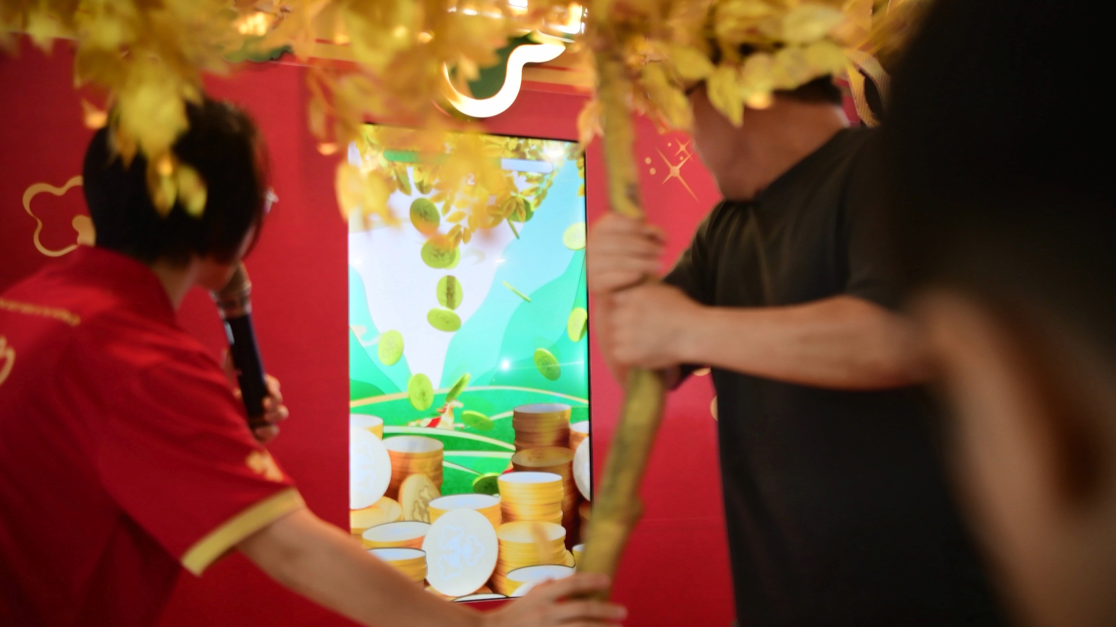 People gathered around a golden prosperity tree and a screen showing green and gold game graphics.