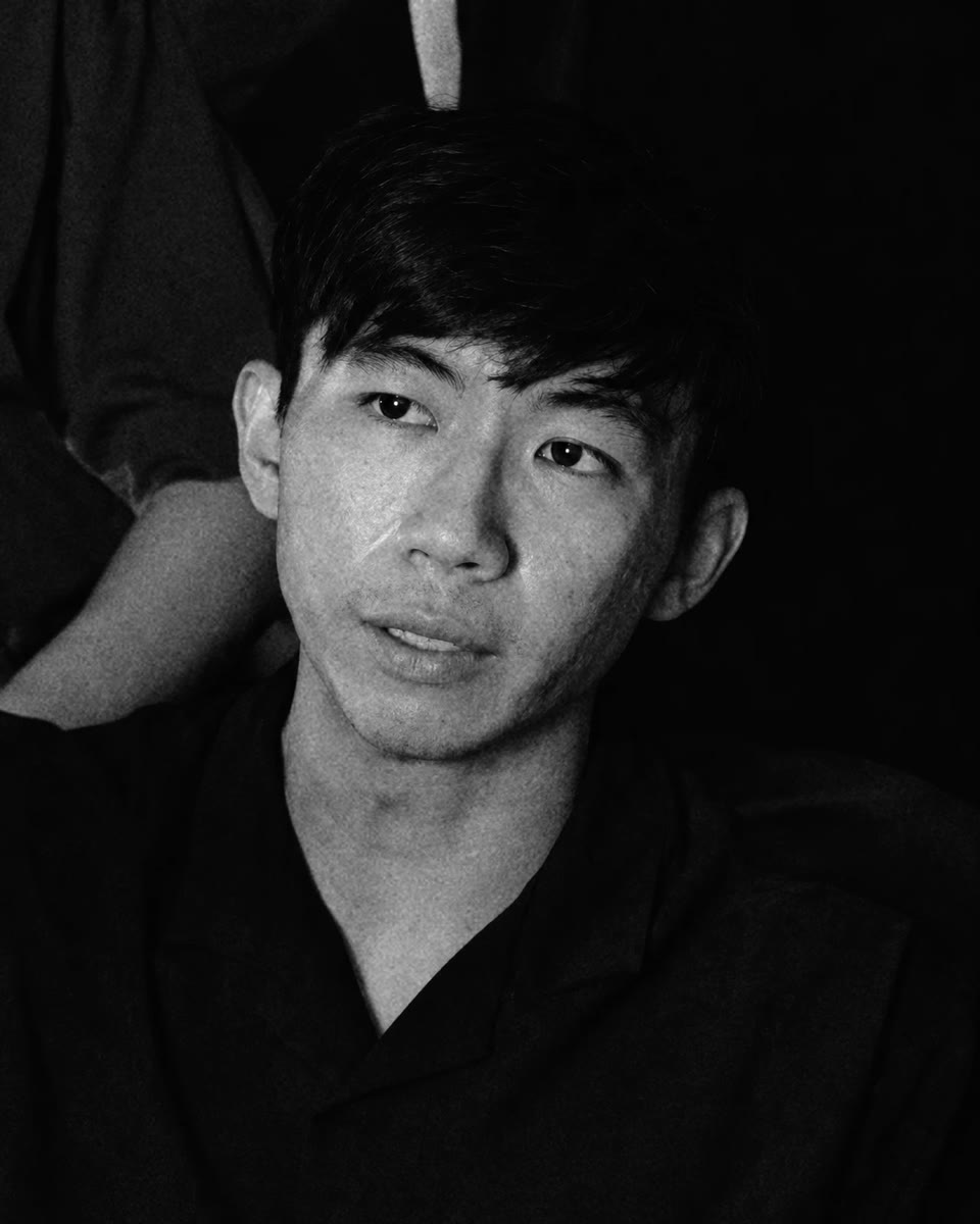 Nicholas Lim in black and white, seated and looking towards the camera.