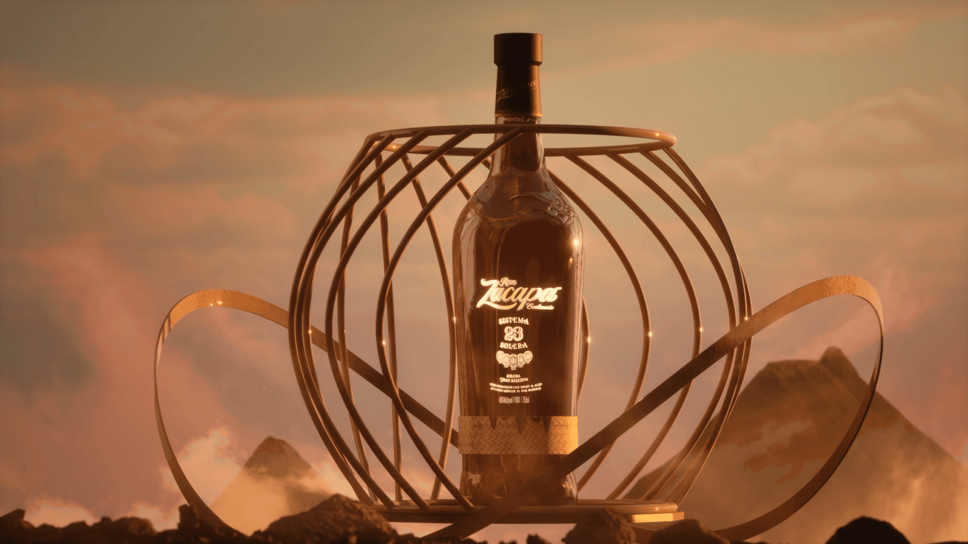 Zacapa rum bottle enclosed by sculptural golden ribbons against a warm, mountainous backdrop.